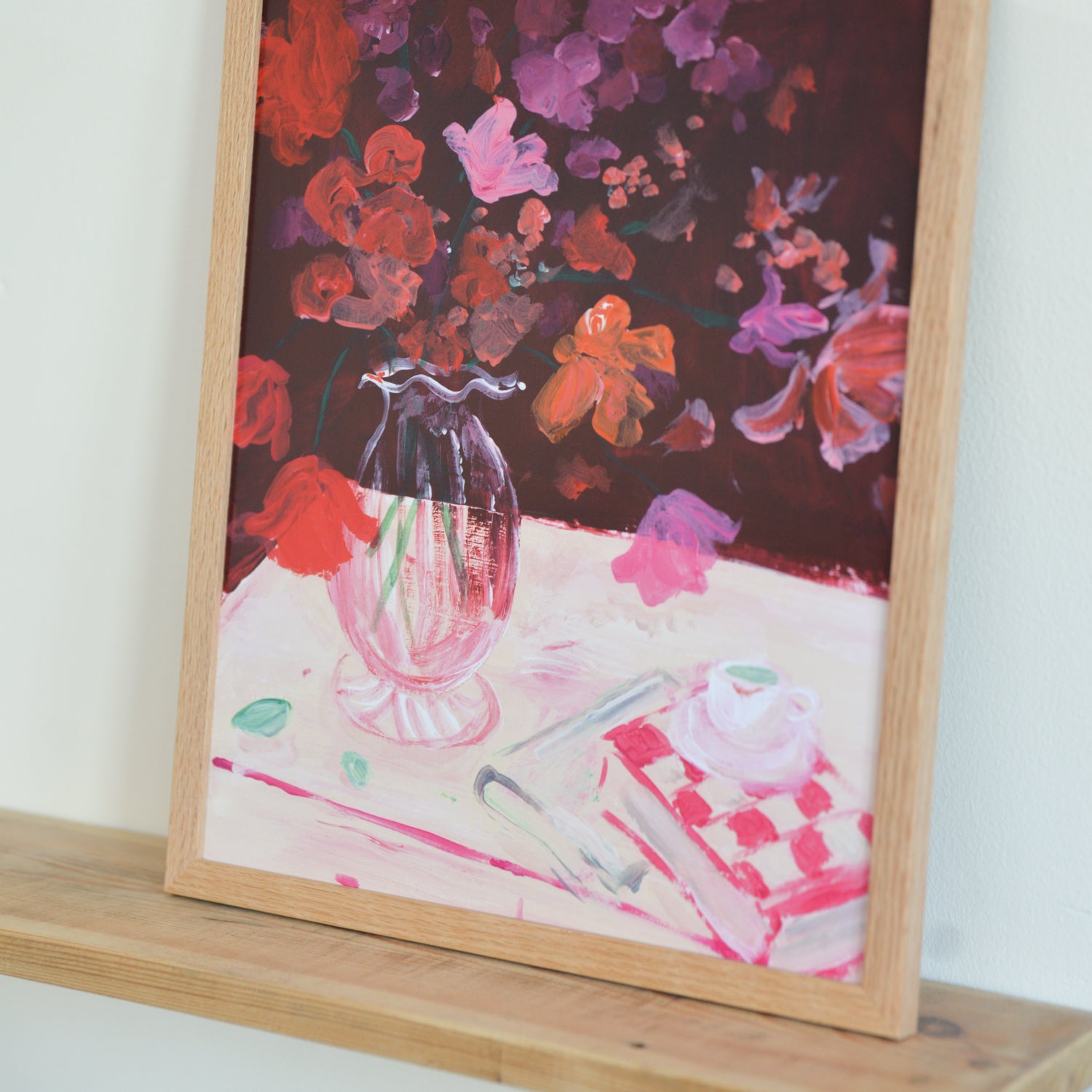 Framed painting of a vase with flowers and a checkered tablecloth.