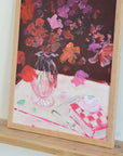 Framed painting of a vase with flowers and a checkered tablecloth.