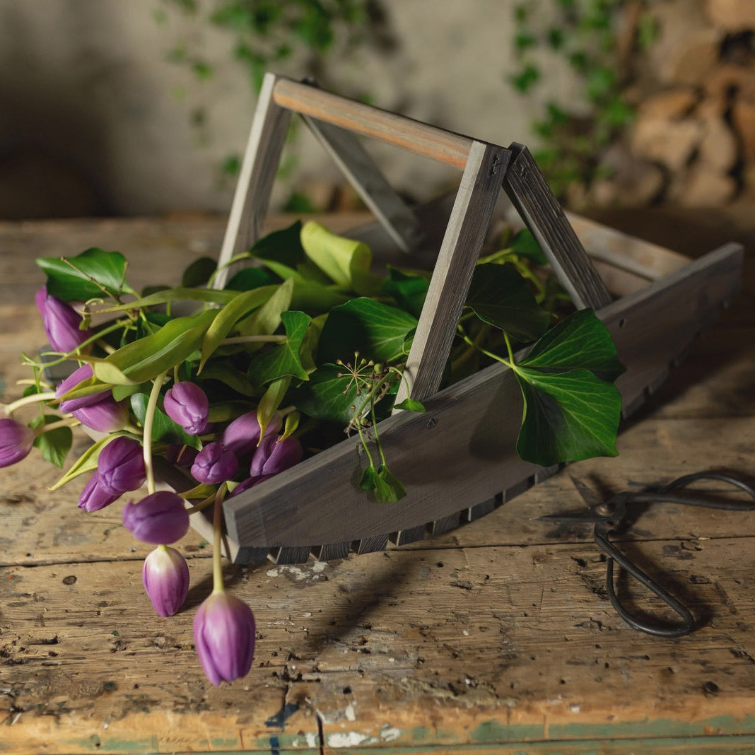 Purple flowers in a rustic wooden tool box on a wooden surface with a blurred background