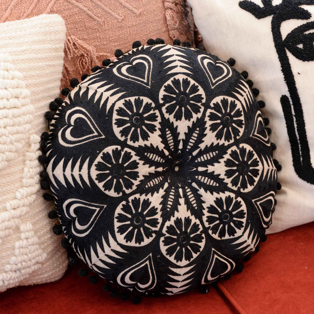 Black and neutral off white round filled cotton  cushion embroidered with black pom pom tassels by Bloomingville
